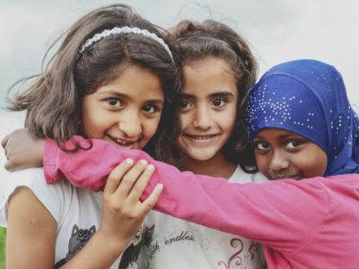 Tres niñas refugiadas se abrazan y sonríen