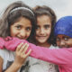 Tres niñas refugiadas se abrazan y sonríen