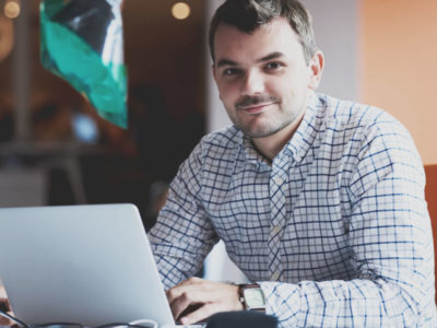 Hombre emprendedor joven con camisa de cuadros trabajando con ordenador portátil